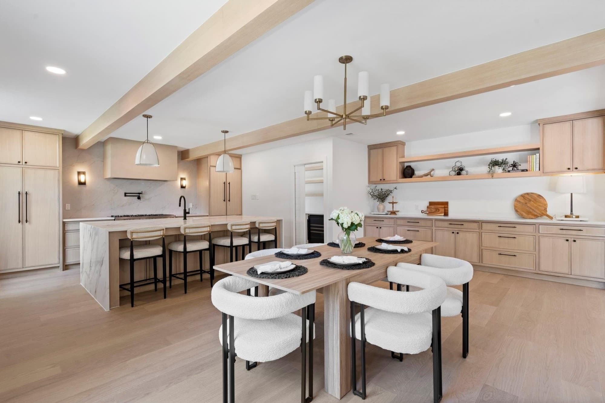 Open kitchen and dining area with white oak cabinetry and exposed beams