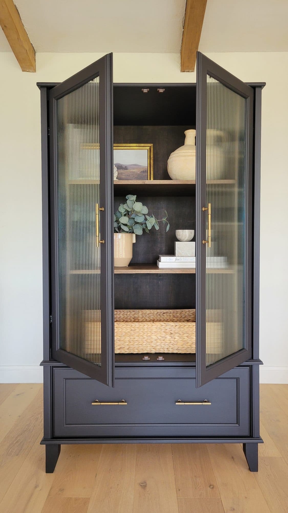 Refinished black cabinet with reeded glass doors and brass pulls