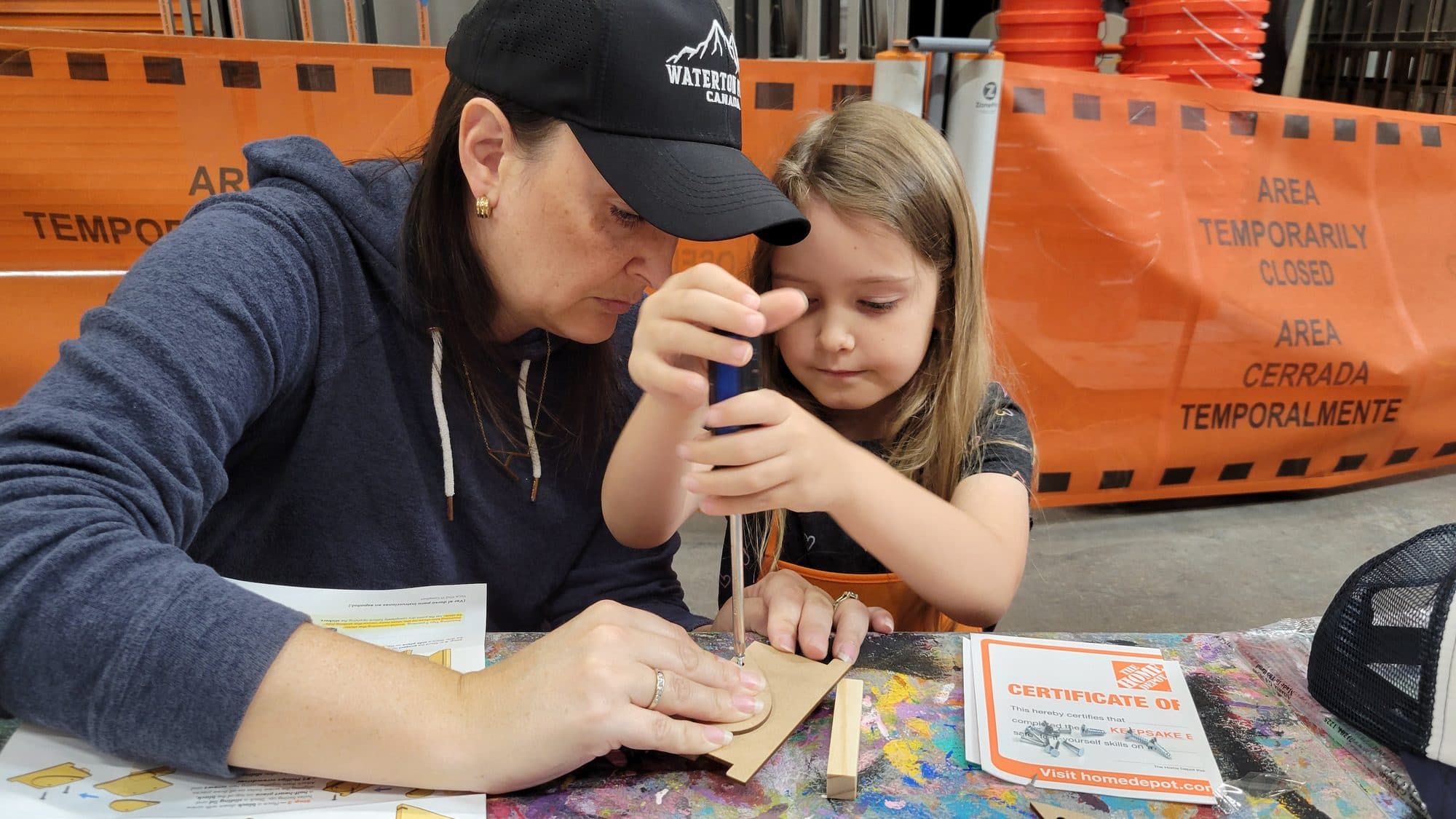 Savana helping a young builder with a screwdriver at a kids' workshop
