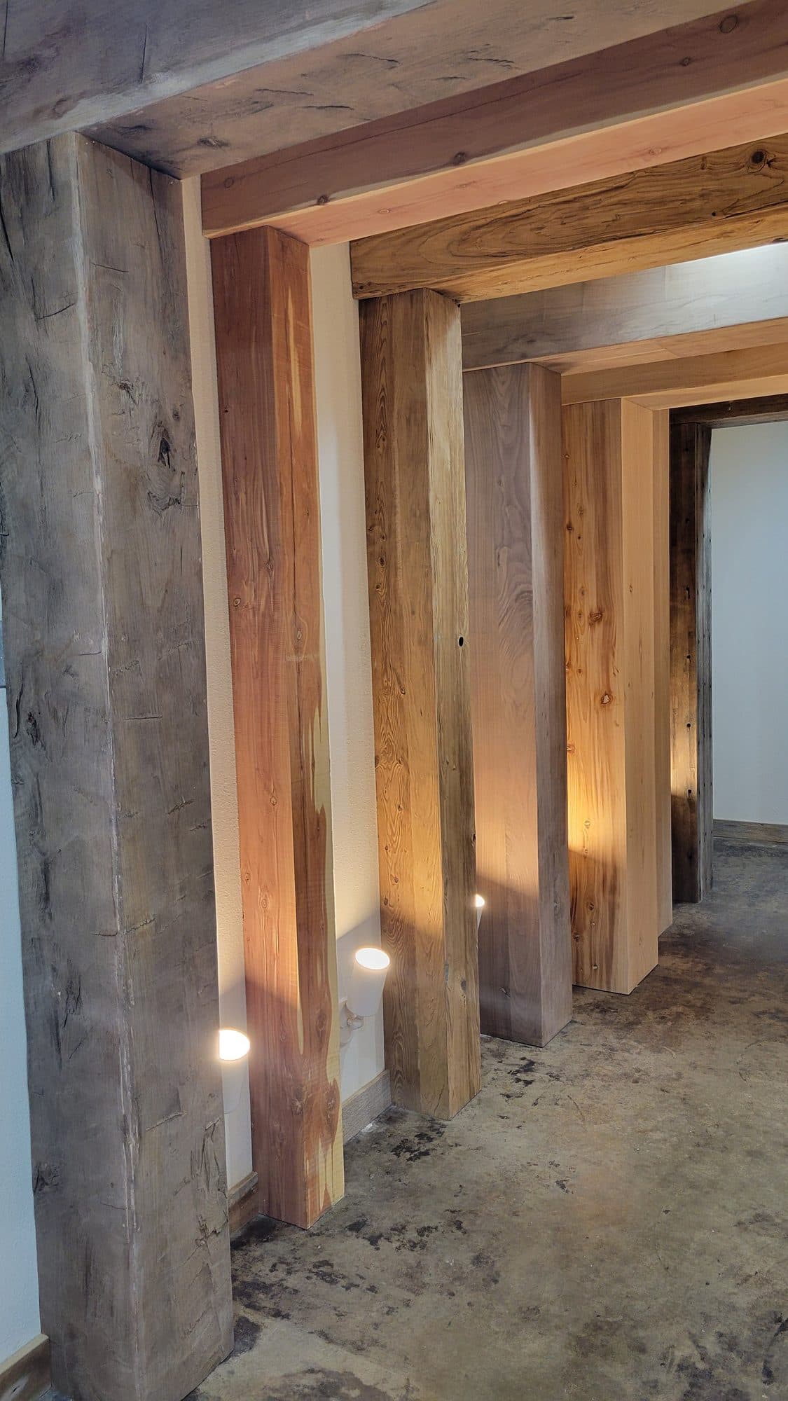 Corridor of reclaimed timber posts and beams with floor uplighting