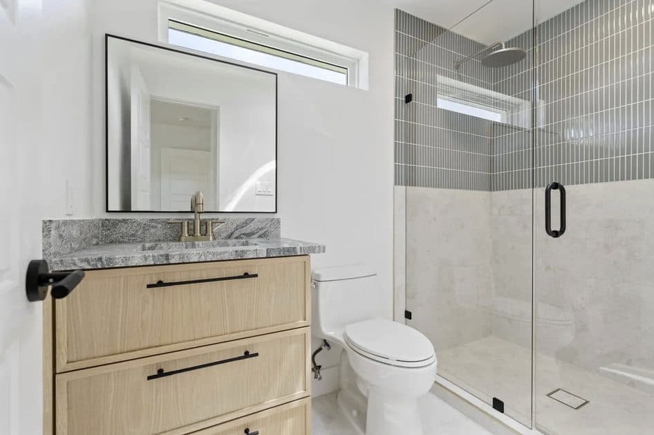 Guest bath with oak vanity and vertical sage-green shower tile