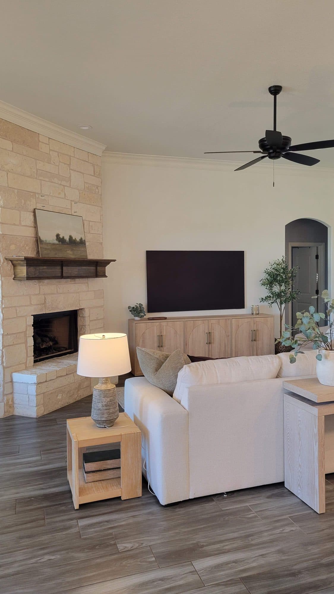Stone fireplace with a wood mantel, side table, and lamp