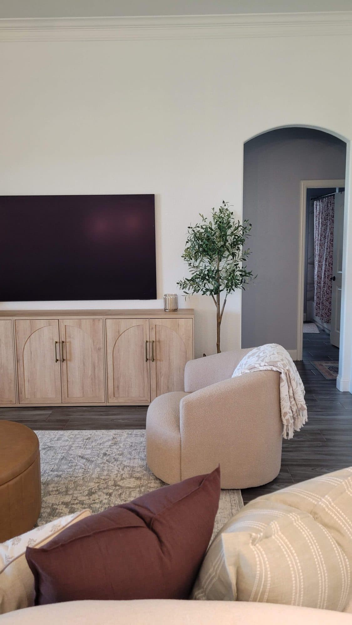 Arched-door oak console with an olive tree and boucle swivel chair